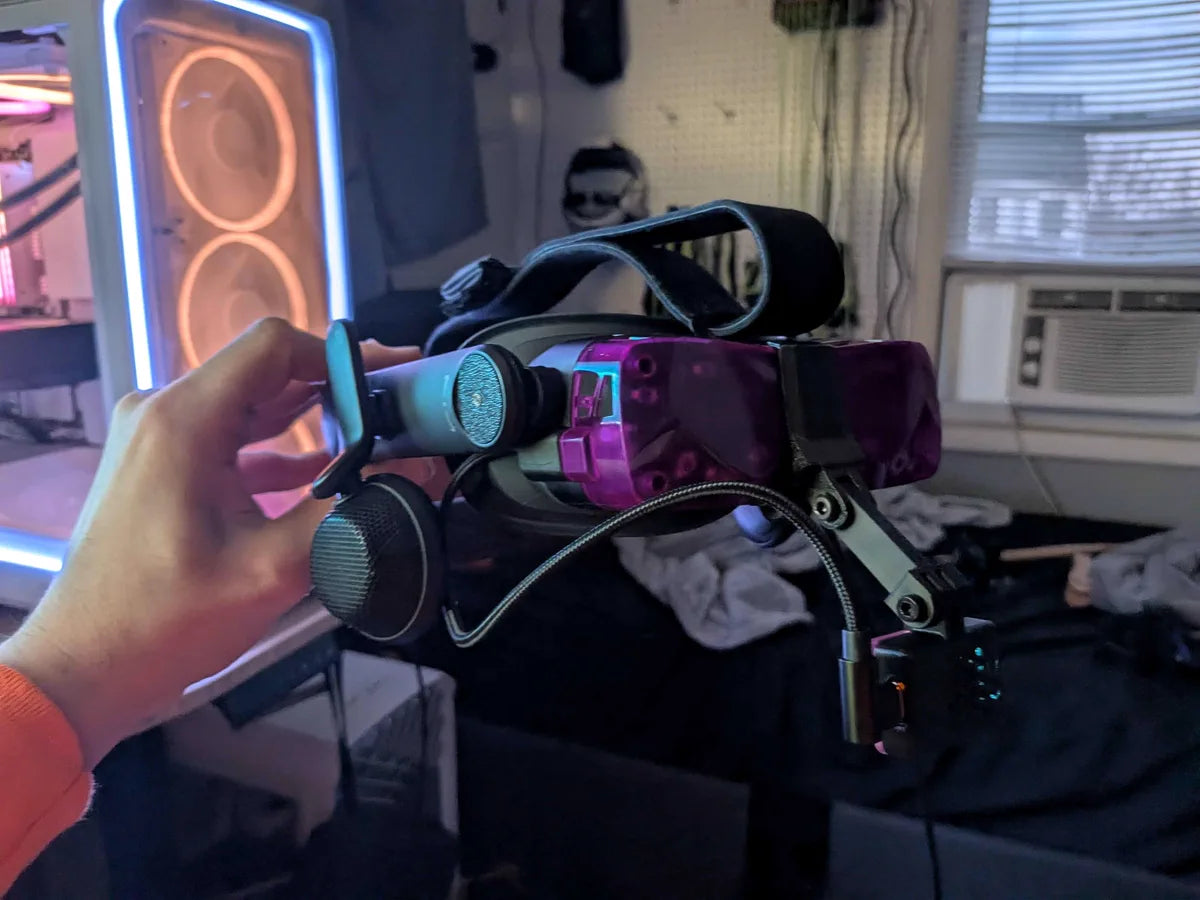 A purple Beyond 2 with a cyan audio strap held up in front of a lit desk setup